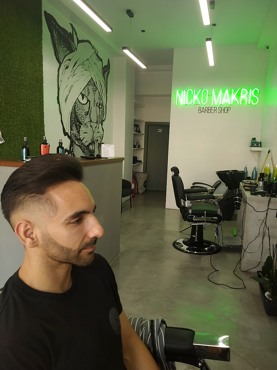 Skin fade με slick back, δίπλα στο neon.